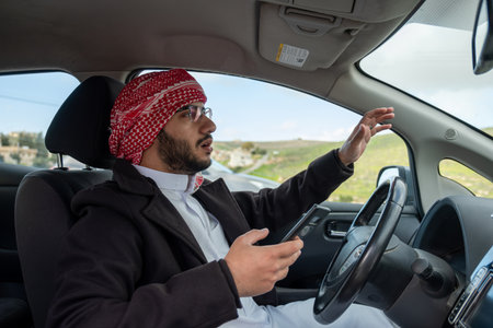 young arab male using phone while driving looking maps or calling