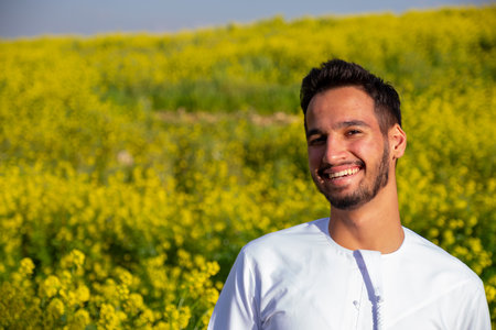 Arabian male enjoy healthy lifestyle in nature between yellow flowers in the field having fresh air during springの写真素材