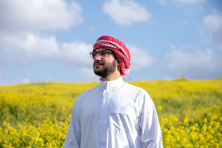 An individual sits in a golden field of flowers at sunrise, arms raised in positivity. The fresh spring air and vibrant sky symbolize health and freedom capturing a moment of harmony and adventureの写真素材
