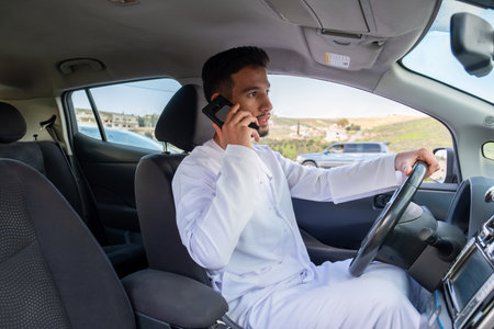 Young arab male using mobile phone while drivingの写真素材
