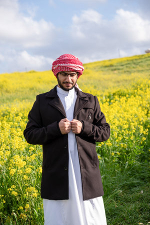 An Arab people enjoys a spring picnic in a meadow near Abu Dhabi. Seated on chairs, they savor cups of coffee under a blue sky with scattered cloudsの写真素材