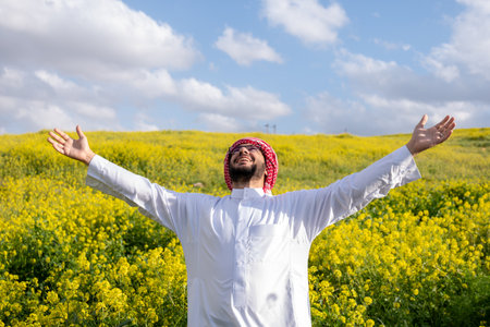 Arabian male enjoy healthy lifestyle in nature between yellow flowers in the field having fresh air during springの写真素材