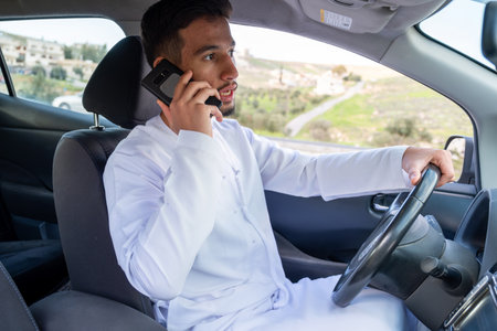 Young arab male using mobile phone while drivingの写真素材