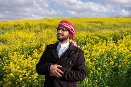 Arabian male enjoy healthy lifestyle in nature between yellow flowers in the field having fresh air during springの写真素材