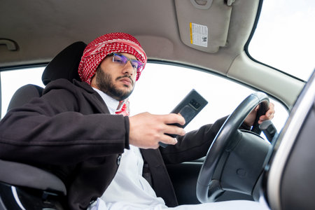 young arab male using phone while driving looking maps or callingの写真素材