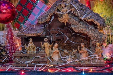 A traditional Nativity scene depicting the birth of Jesus, featuring figurines of Mary, Joseph, baby Jesus in a manger, shepherds, wise men, an angel, and animals, illuminated by festive lightsの写真素材