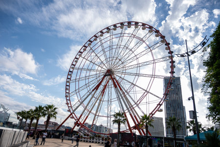 Red and White Ferris Wheel Against Blue and Cloudy Sky with Copy Spaceの写真素材