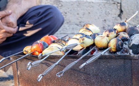 vegetables grilling on charcoal with onion and tomato with fire and smokeの写真素材