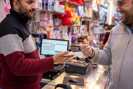 A man makes contactless payments at a bookshop or gift shop using his smartwatch, seamlessly utilizing NFC or WiFi technology, without the need for physical touchの写真素材
