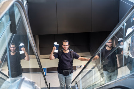 Young male holding his passport at the airport ready for new adventure with airplane in the backgroundの写真素材