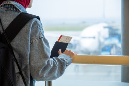 Arabic muslim female at the airport holding her passport and looking at airplaneの写真素材
