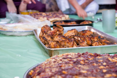 grilled Chicken tray ready to be eaten with people hands and musakhan breadの写真素材