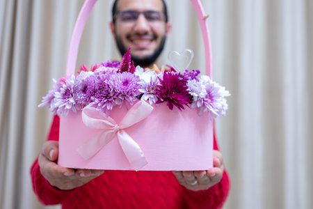 a young male is holding a flower bouquet in a pink boxの写真素材
