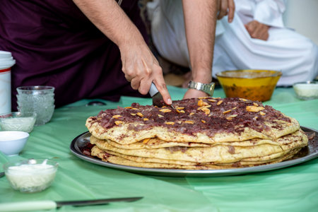 Man hands cutting musakhan bread with knife for guests and family to eat togetherの写真素材