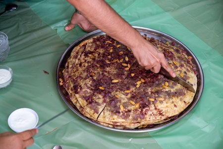 Man hands cutting musakhan bread with knife for guests and family to eat together