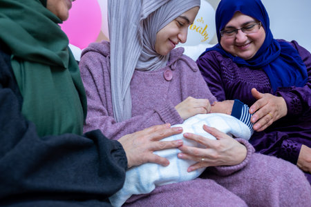 Females are celebrating a new baby and holding it indoors, with gifts and balloons around