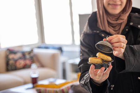 muslim Female hands holding eid sweets in home with smile on her faceの写真素材