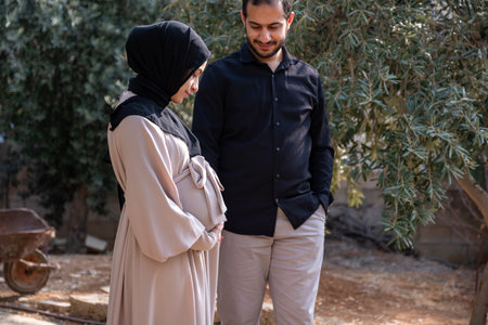 A husband walks with his pregnant wife in the park, exchanging loving glances and feeling excited about the approaching time of birthの写真素材