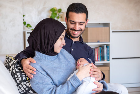 Arabic Muslim parents share a tender moment with their newborn daughter, radiating love and joy in...