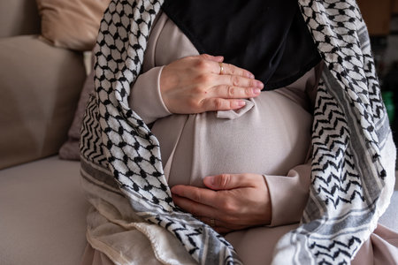 Palestinian pregnant female wearing keffiyeh on couchの写真素材