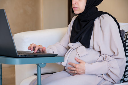 Pregnant woman working from home checking internet about pregnancy and have doctors advice through internet onlineの写真素材