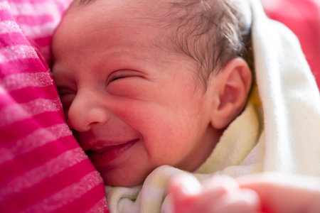 mother cuddling her newborn with smile on their faces and adorable look on baby faceの写真素材