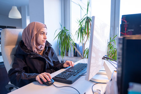 Muslim female working in office using computer with white background, represent power of arabian womanの写真素材