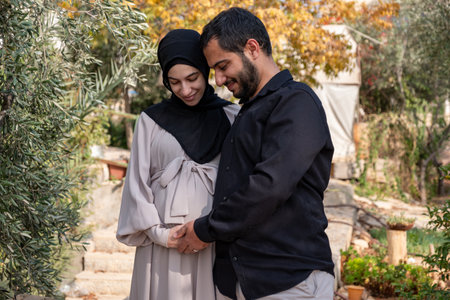 male touching his wife belly in garden and feeling excited for his new babyの写真素材