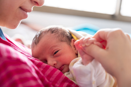 mother cuddling her newborn with smile on their faces and adorable look on baby faceの写真素材