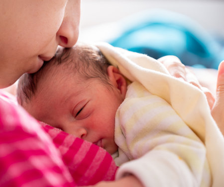 mother cuddling her newborn with smile on their faces and adorable look on baby face