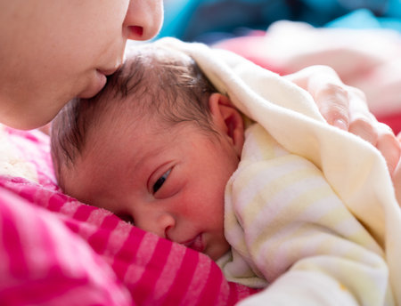 mother cuddling her newborn with smile on their faces and adorable look on baby faceの写真素材