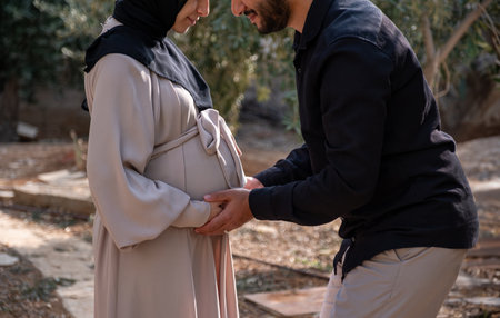 A husband walks with his pregnant wife in the park, exchanging loving glances and feeling excited...
