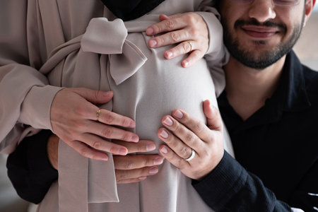 Arabian man is listening to his beautiful pregnant wife's tummy and smilingの写真素材