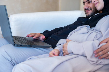 male and pregnant female chatting about pregnancy and how to rise child while using laptop  in home...