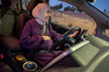 Pregnant arabic muslim woman driving car at night wearing winter clothes ,hijab and seat belt...