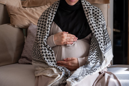 Palestinian pregnant female wearing keffiyeh on couchの写真素材