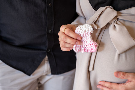 Pregnant female holding small wool knitted clothes