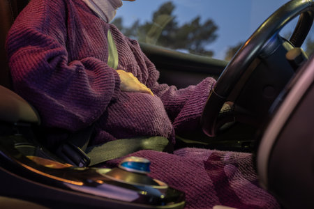 Pregnant arabic muslim woman driving car at night wearing winter clothes ,hijab and seat belt...