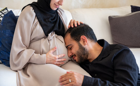 A picture of the husband and his pregnant wifeâs belly, and the wife pats her husbandâs headの写真素材