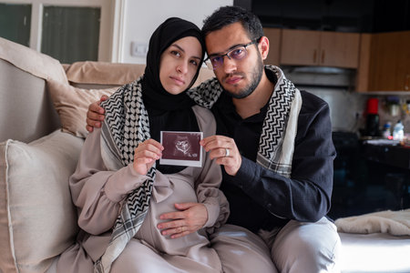 Husband and his wife holding sonography photo for their fetus while wearing Palestinian keffiyeh in...