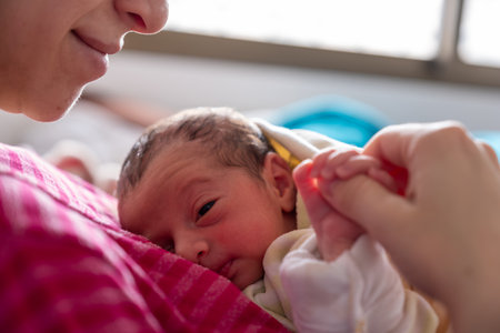 mother cuddling her newborn with smile on their faces and adorable look on baby faceの写真素材