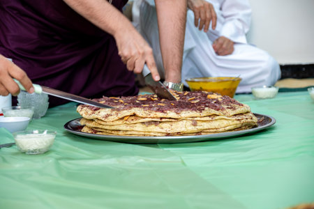 Man hands cutting musakhan bread with knife for guests and family to eat togetherの写真素材