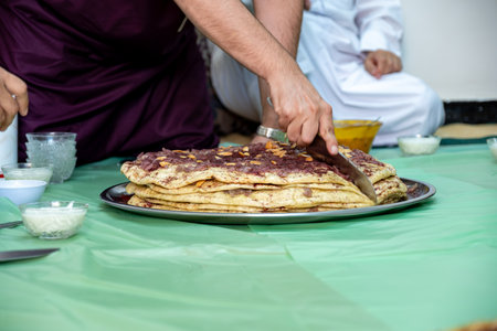 Man hands cutting musakhan bread with knife for guests and family to eat togetherの写真素材