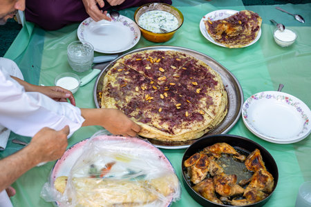Family and friends gathering together at home for eating palestinian traditional musakhan