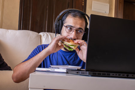 Young arabic man eating while working at home