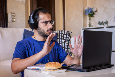 Young arabic man eating while working at home