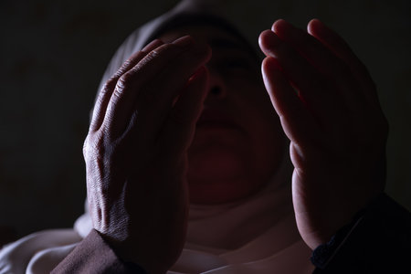 A Muslim woman raises her prayers to God to remove the affliction and illness from her and to...