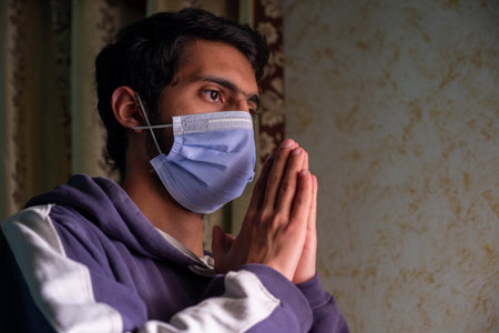 Male wearing mask and praying for allah to protect him from diseases and help him being well