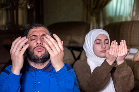 muslim couples praying together asking allah for mercy and forgiveness ,wearing casual clothes in homeの写真素材