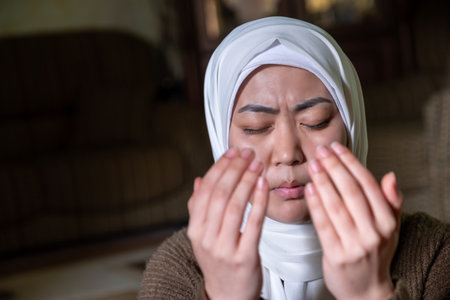 muslim couples praying together asking for mercy and forgiveness, wearing casual clothes in homeの写真素材